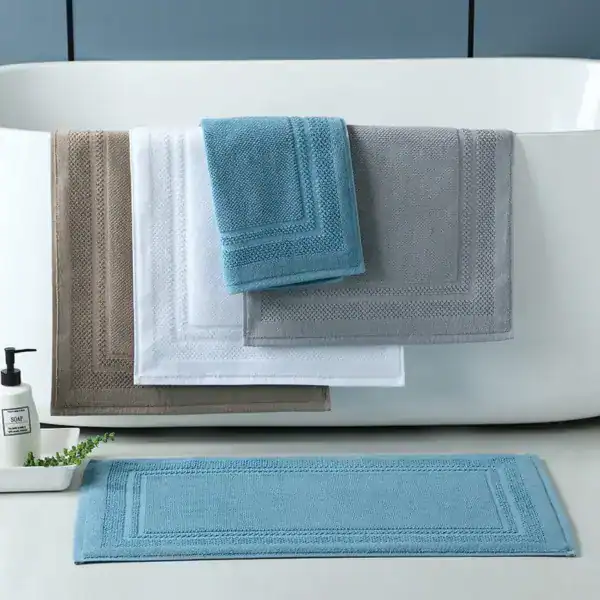 Badematte Baumwolle in verschiedenen Farben, stilvoll auf Badewanne und Boden platziert.