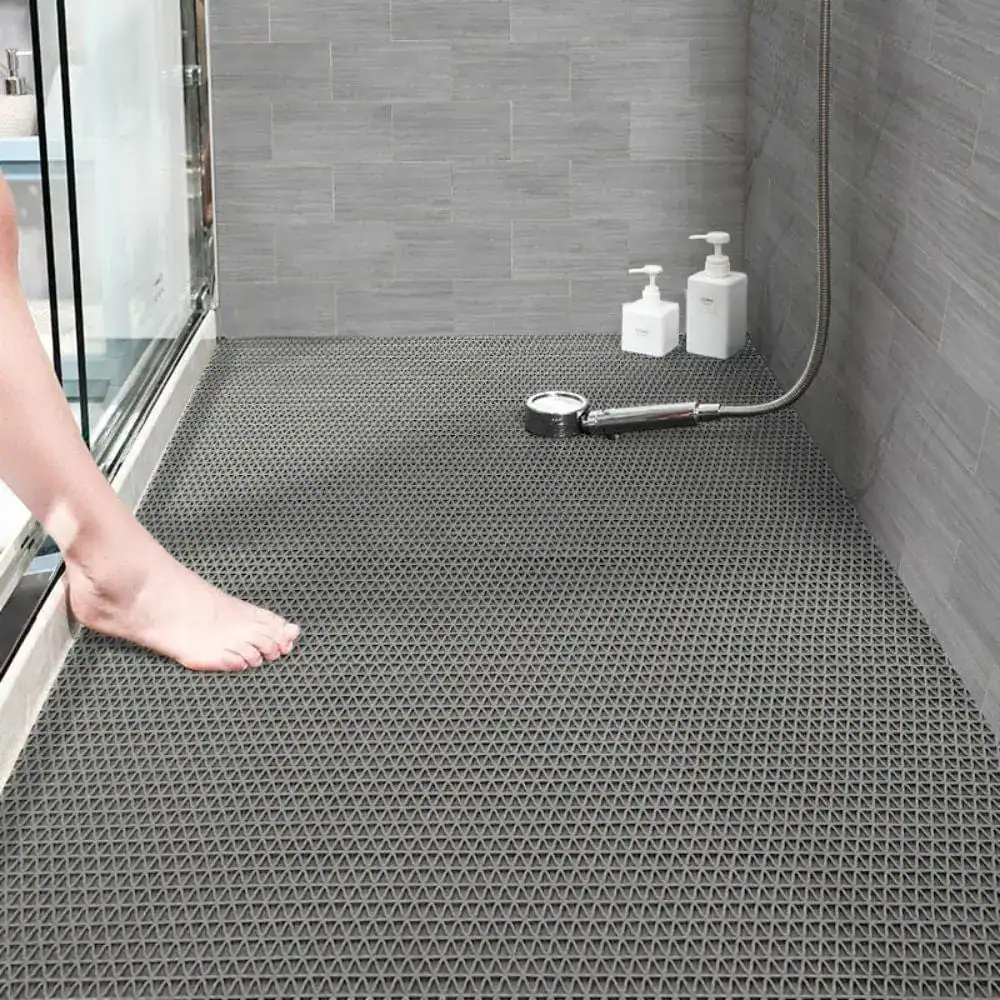 Graue Badematte Dusche mit rutschfestem Dreieckmuster, Fuß darauf stehend.