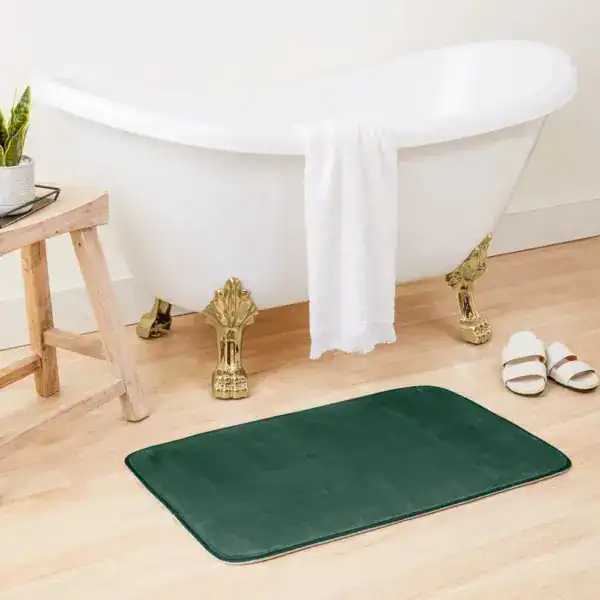Flaschengrüne Badematte vor Badewanne mit goldfarbenen Füßen, stilvolles Badezimmer.
