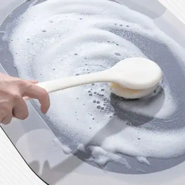 Graue Badematte mit Muster, leicht zu reinigen, Schaumbürste in Aktion.