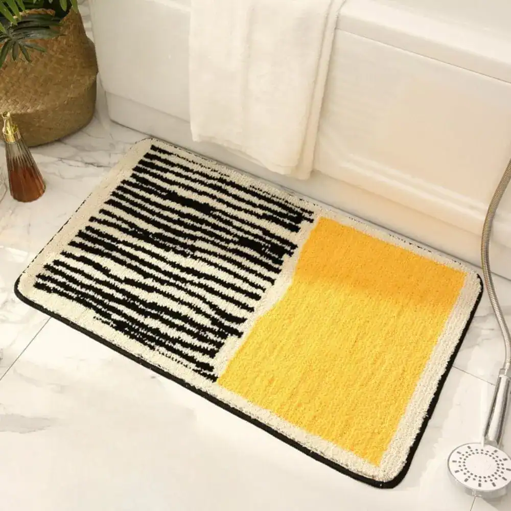 Moderne Badematte mit schwarz-weißem Streifenmuster und gelbem Feld, ideal für stilvolle Badezimmer.