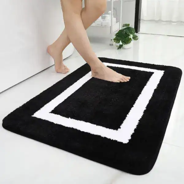 Schwarze Badematte mit weißem Rahmen, weicher Flor, ideal für Badezimmer.