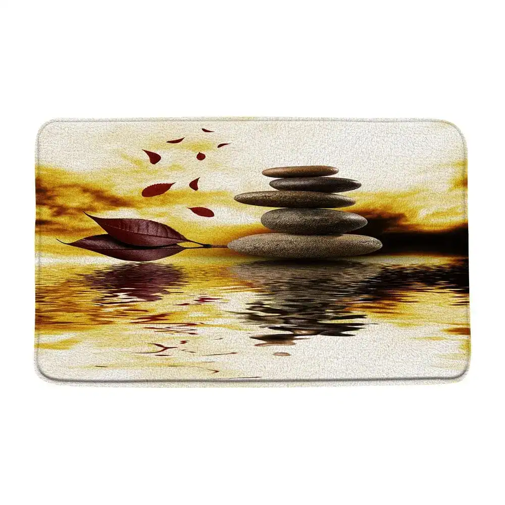 Wellness-Badematte mit Steinpyramide und Herbstblättern im Wasserreflex.