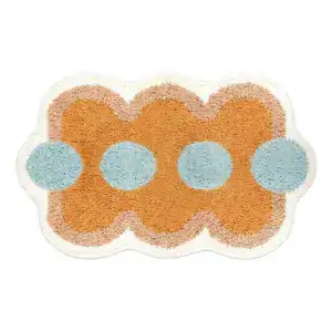 Orange Badezimmermatte mit blauen Punkten und welligem Rand.