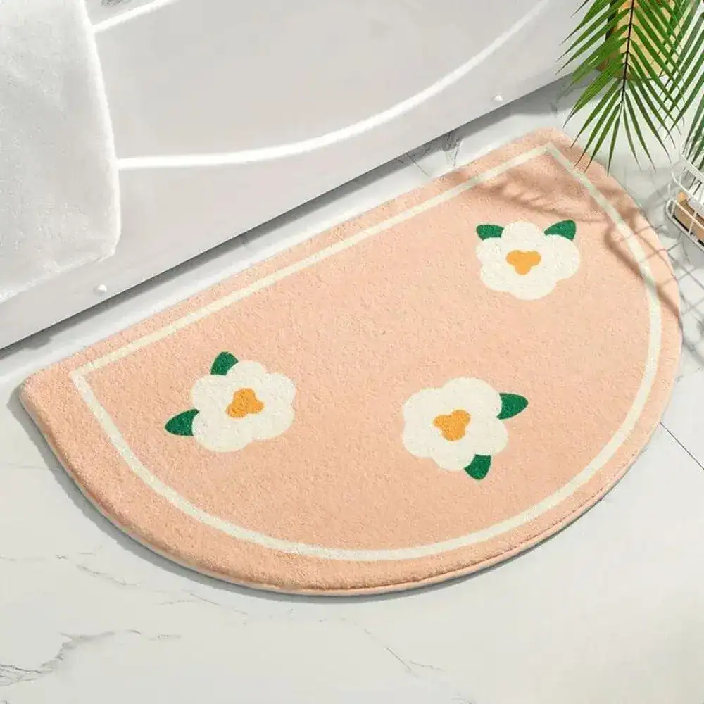 Beige Badezimmermatte mit Blumenmuster vor Badewanne.
