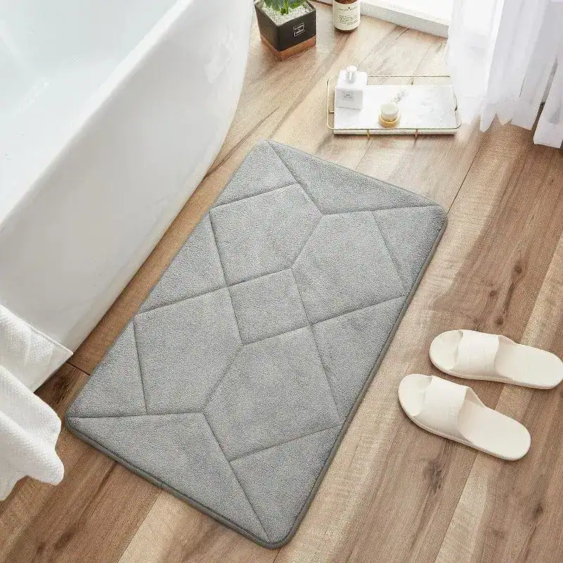 Antirutsch-Badezimmerteppich grau mit geometrischem Muster vor Badewanne.