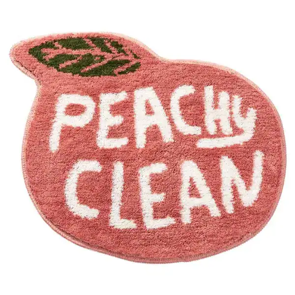 Apricot-farbener Badezimmerteppich mit Aufschrift 'PEACHY CLEAN' in Form einer Pfirsich.