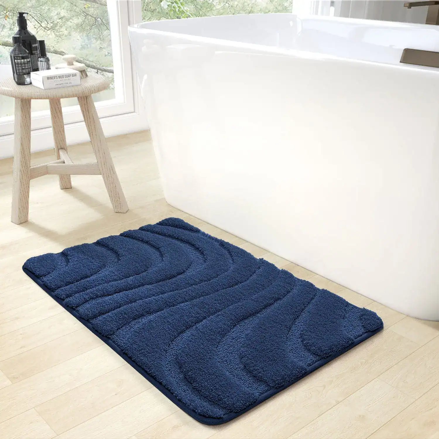 Blauer Badezimmerteppich mit Wellenmuster vor weißer Badewanne.