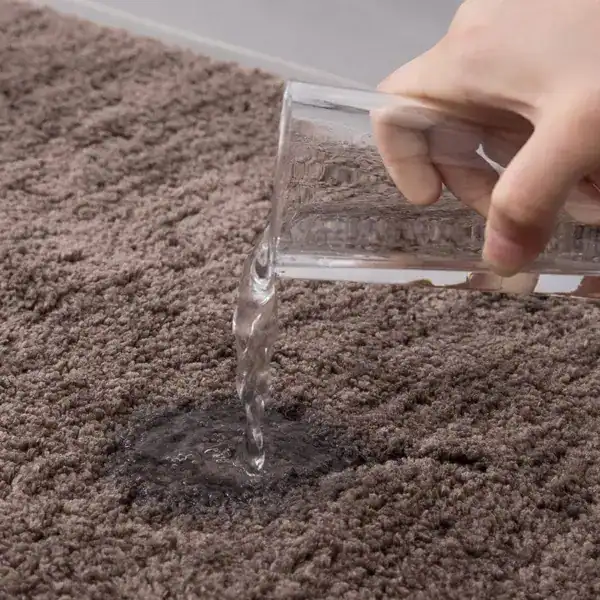 Brauner Badezimmerteppich mit Wasser aufgetragen, Test auf Wasseraufnahme und Absorptionsfähigkeit.
