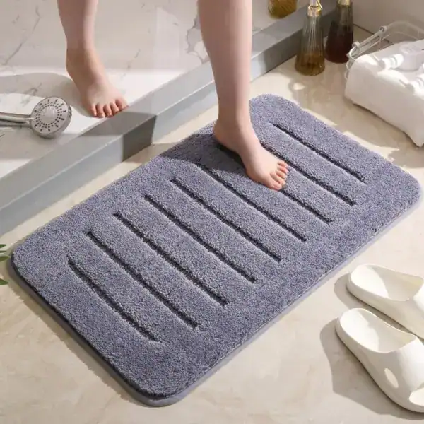 Grauer Badezimmerteppich mit Drainage-Strukturen für optimale Feuchtigkeitsableitung.