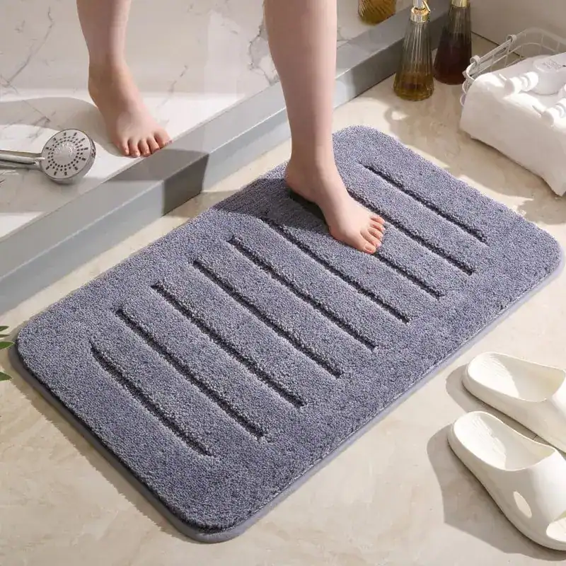 Grauer Badezimmerteppich mit Drainage-Strukturen für optimale Feuchtigkeitsableitung.