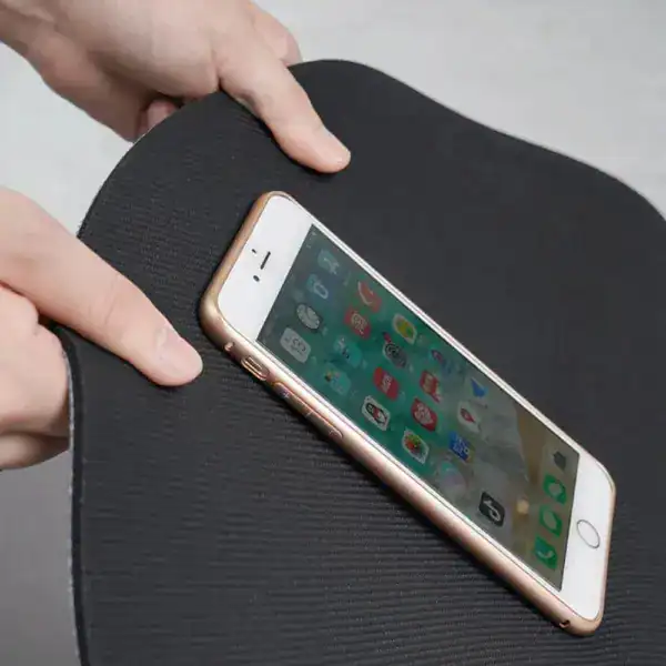 Grauer Badezimmerteppich mit weißer Naht, Smartphone darauf platziert.