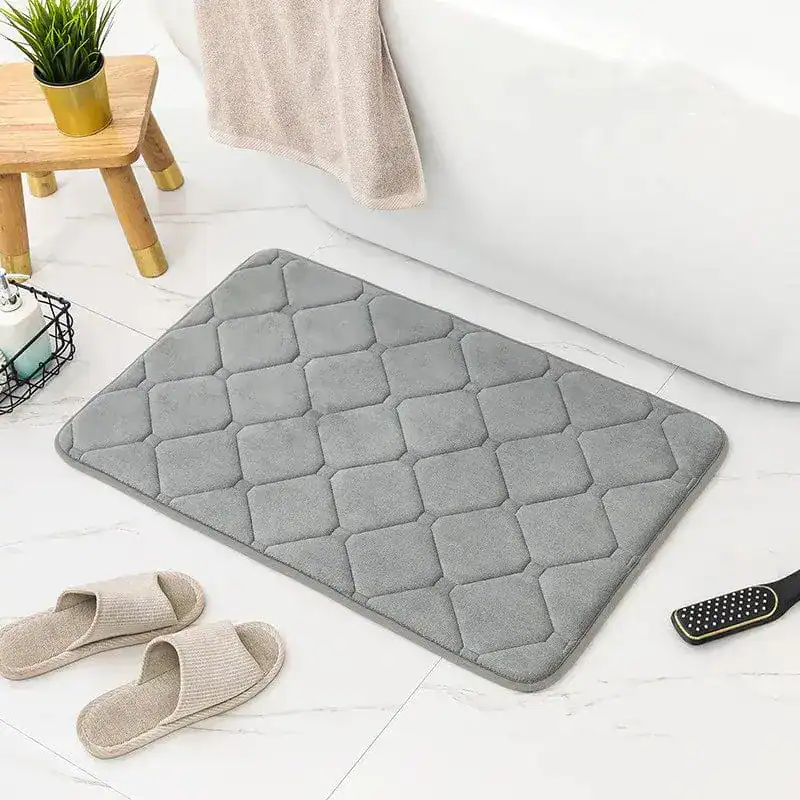 Grauer Memory Foam Badezimmerteppich mit Quilt-Struktur vor Badewanne.