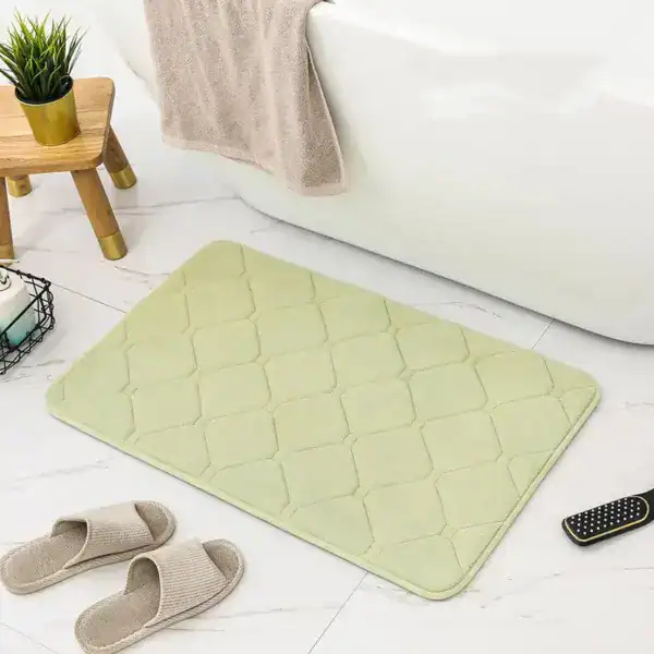 Grüner Memory Foam Badezimmerteppich mit geometrischem Muster vor Badewanne.