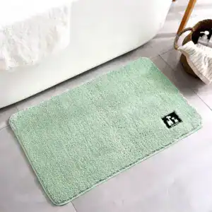 Mintgrüner Badezimmerteppich mit weicher Oberfläche vor Badewanne.