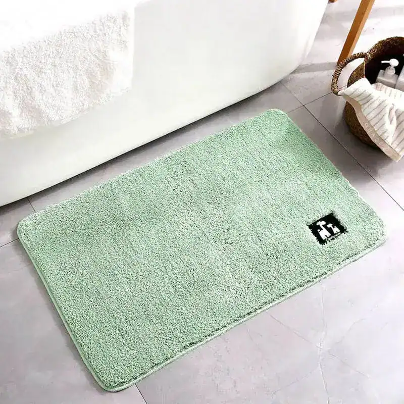 Mintgrüner Badezimmerteppich mit weicher Oberfläche vor Badewanne.