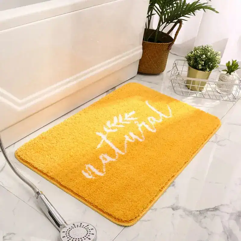 Gelber Badezimmerteppich mit Aufdruck 'natural' vor Badewanne.