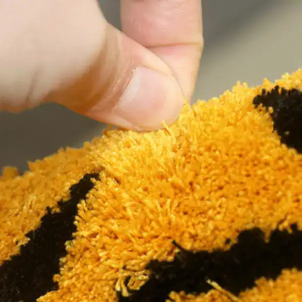 Badezimmerteppich mit organischer Form, orange-schwarzes Muster, weicher Flor.