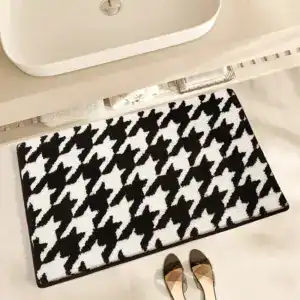 Schwarzer Badezimmerteppich mit Houndstooth-Muster unter Waschbecken.
