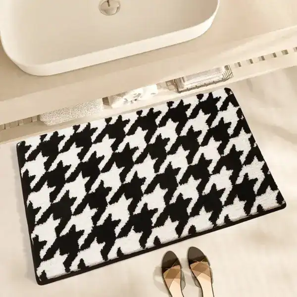 Schwarzer Badezimmerteppich mit Houndstooth-Muster unter Waschbecken.