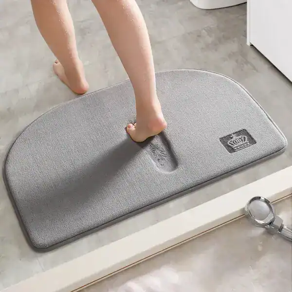 Brauner Badteppich mit Fußabdruck-Design und Krone-Logo für Komfort im Badezimmer.