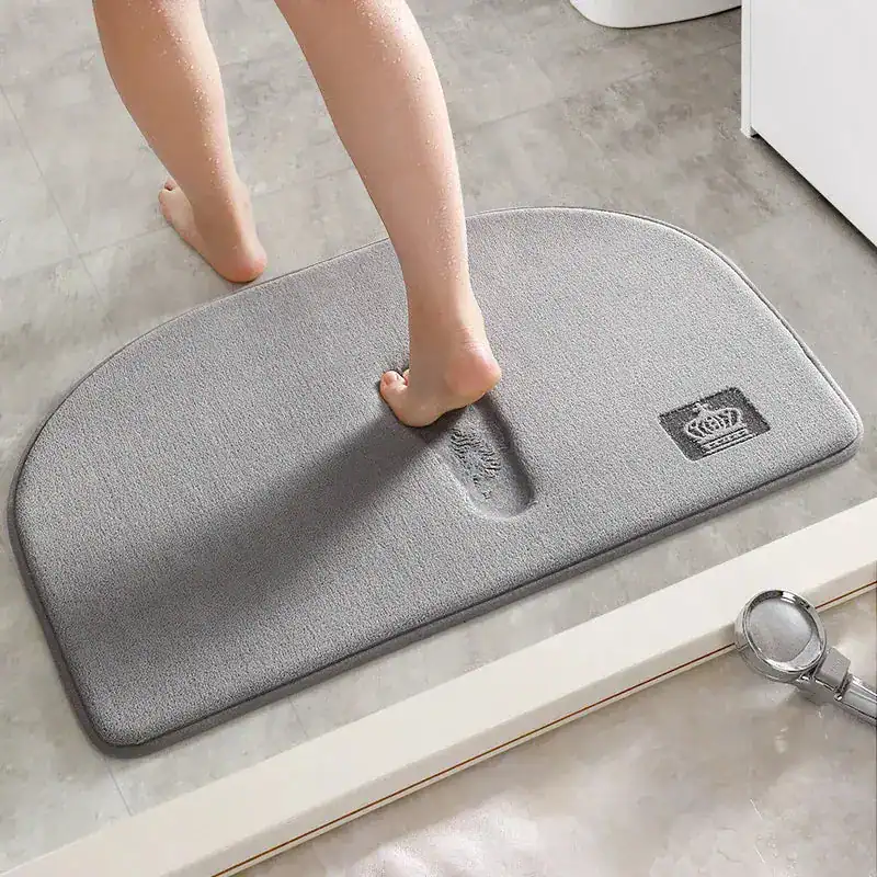 Brauner Badteppich mit Fußabdruck-Design und Krone-Logo für Komfort im Badezimmer.