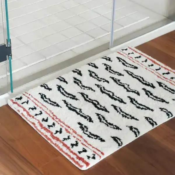 Gemusterter Badteppich mit schwarzen und roten Mustern vor Dusche.