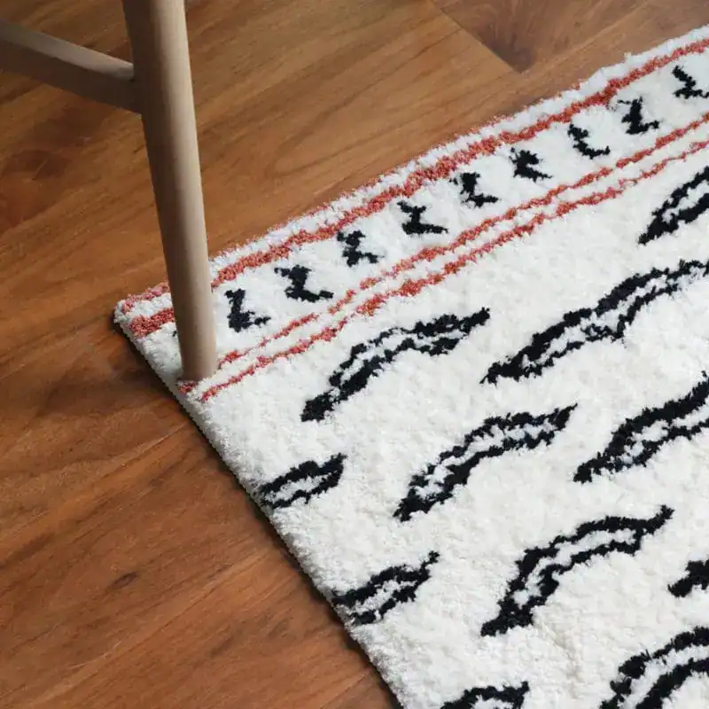 Gemusterter Badteppich mit schwarzen und roten Mustern auf weißem Untergrund.