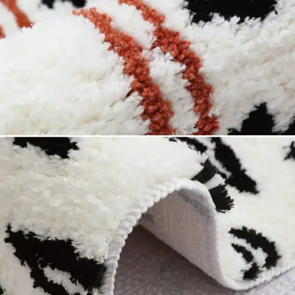 Gemusterter Badteppich mit weichem Hochflor, schwarz-weiß-orange Muster und gerippter Kante.