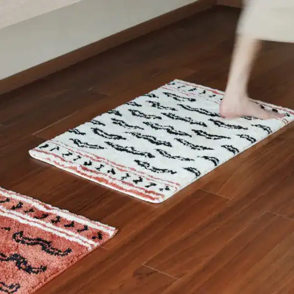 Gemusterter Badteppich mit schwarzen Mustern auf weißem Grund, ideal für Badezimmer.
