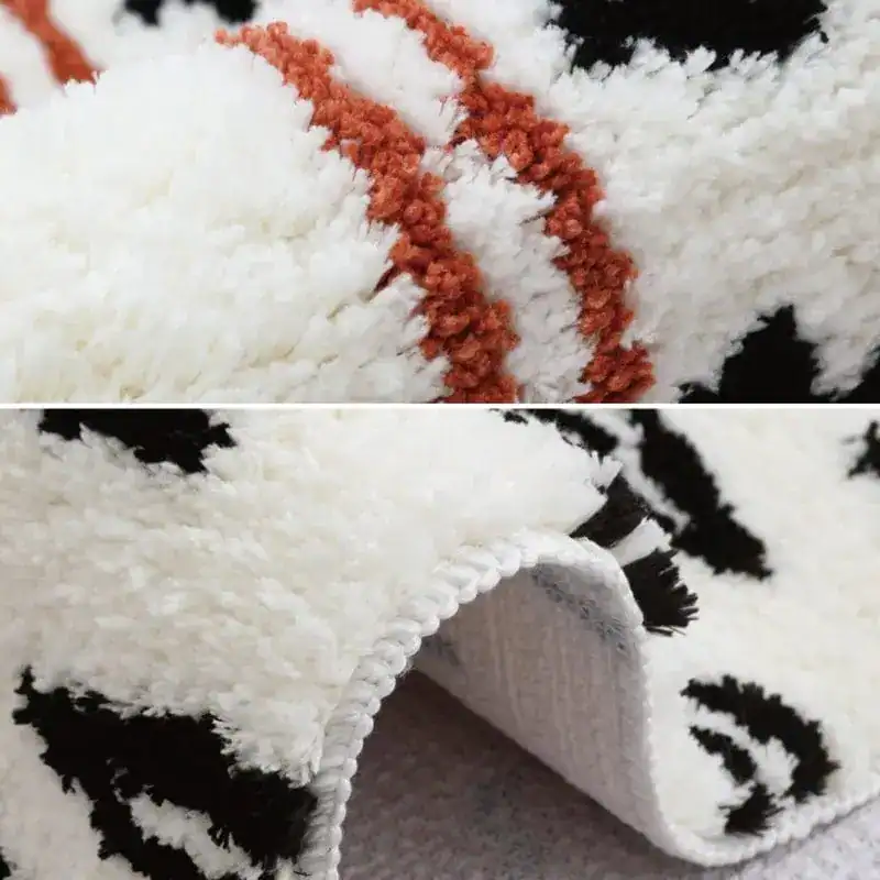 Gemusterter Badteppich mit weichem Hochflor, schwarz-weiß-orange Muster und gerippter Kante.