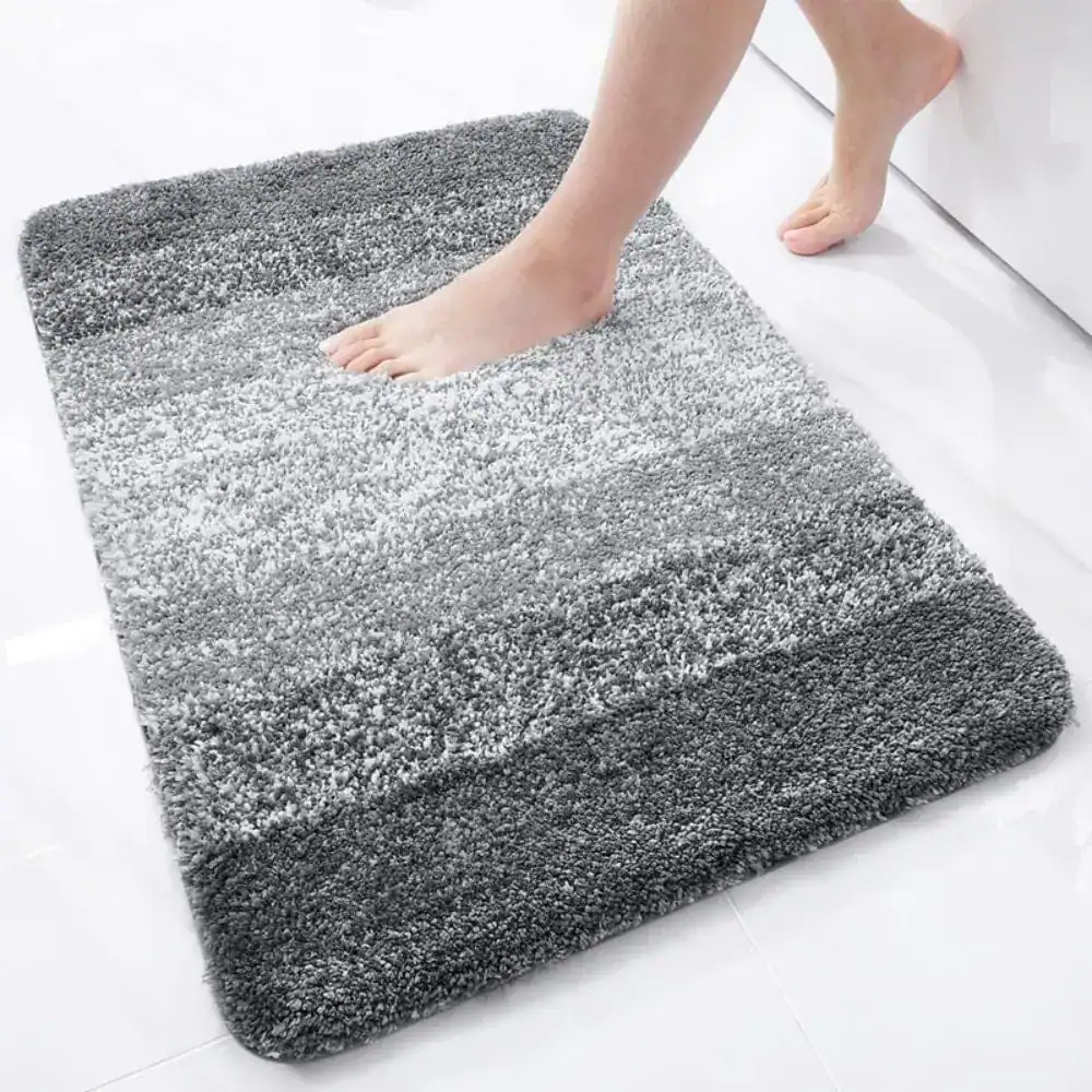Grauer Badteppich mit weicher Hochflor-Optik und Fußabdruck, ideal für Komfort und Stil im Badezimmer.