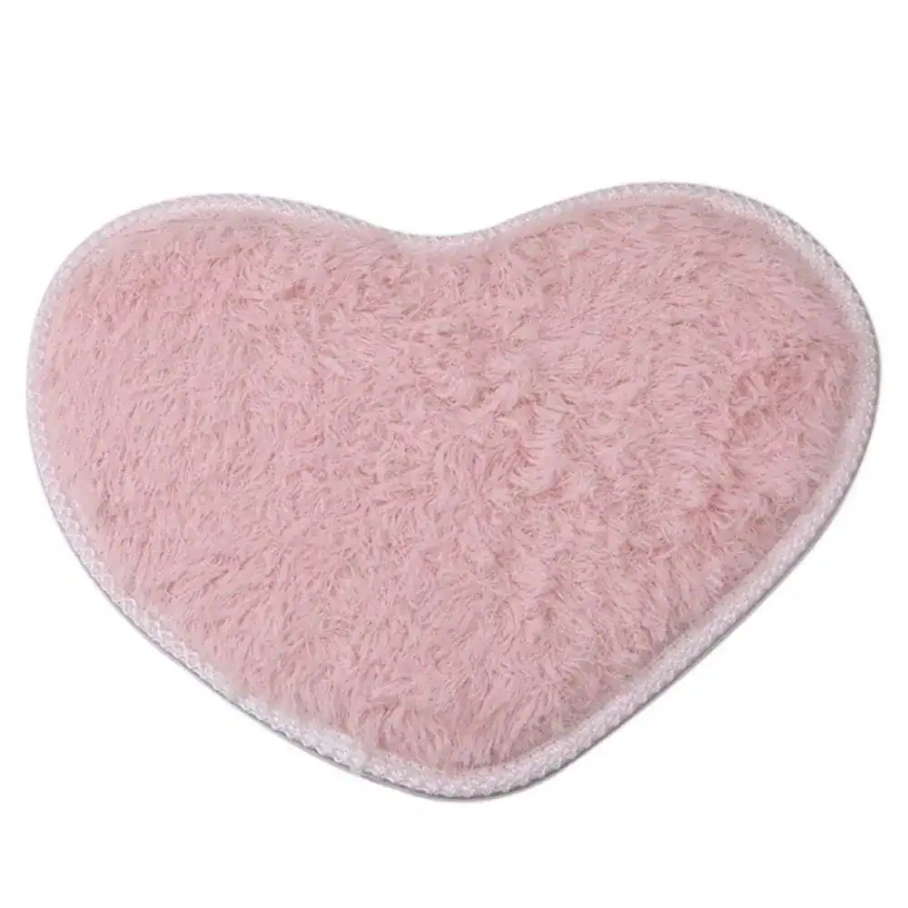 Herzformiger Badteppich in sanftem Rosa mit flauschigem Hochflor und weißer Kante.