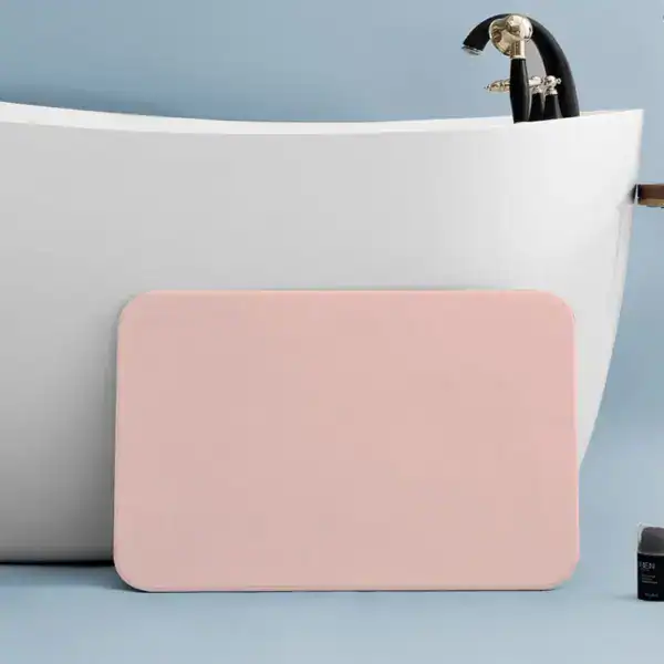 Saugfähiger Badteppich in Rosa vor weißer Badewanne, rutschfest und pflegeleicht.