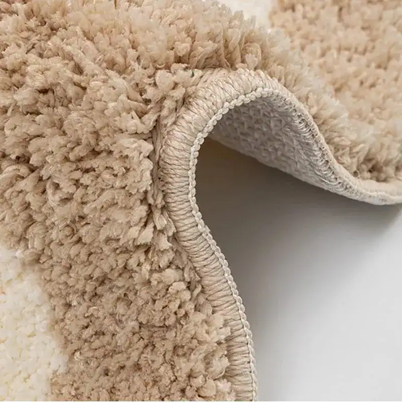 Kleine Badematte mit flauschigem, cremefarbenem Hochflor und geripptem Rand.