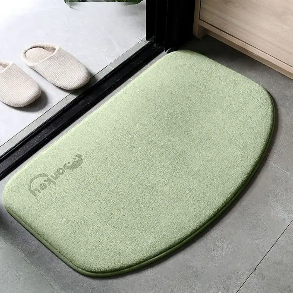 Grüne Mikrofaser Badematte mit abgerundeten Ecken und Logo, ideal für Badezimmer.