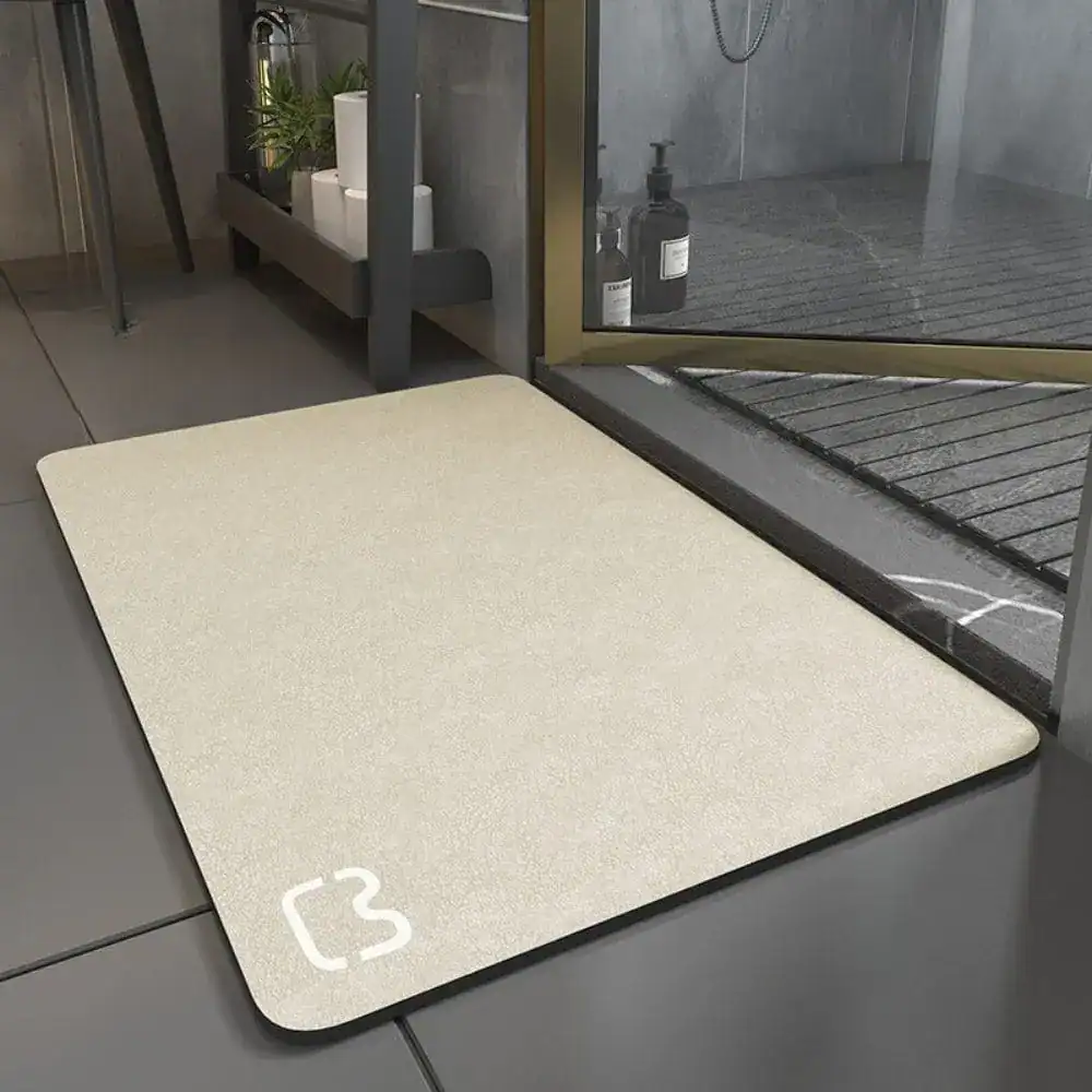 Superabsorbierende Badematte mit Logo, beige Farbe, vor Dusche auf Fliesenboden.
