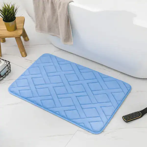 Weichschaum Badematte in Hellblau mit geometrischem Muster vor Badewanne.