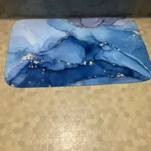 Badematte in Blau mit Marmorierung auf Sechseckfliesen