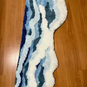 Getuftete Badematte mit Wellenmotiv in Blau und Weiß auf Holzboden