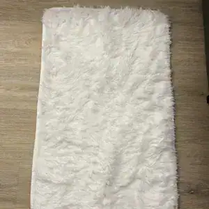 Flauschige Badematte in Weiß auf Holzboden